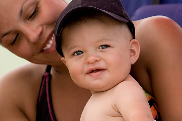 Baby boy sitting on mothers lap stock photo