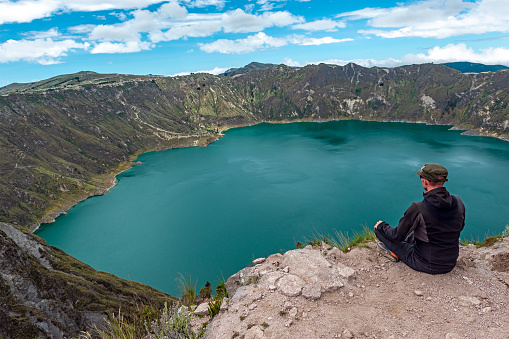 Male tourist hiker looking over Quilotoa Lake along the Quilotoa Lagoon Loop, Andes Mountains, Quito region, Ecuador.
