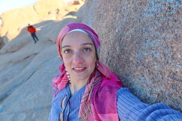 istock A cheerful young woman wearing a purple pullover and a head cover  with hazel eyes taking a selfie in the middle of the rocks of the blue desert in Egypt 1760465639