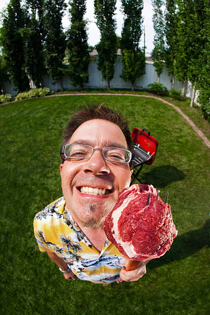 barbecue man This man is very happy with the steak he is about to barbecue. fish eye lens photos stock pictures, royalty-free photos & images