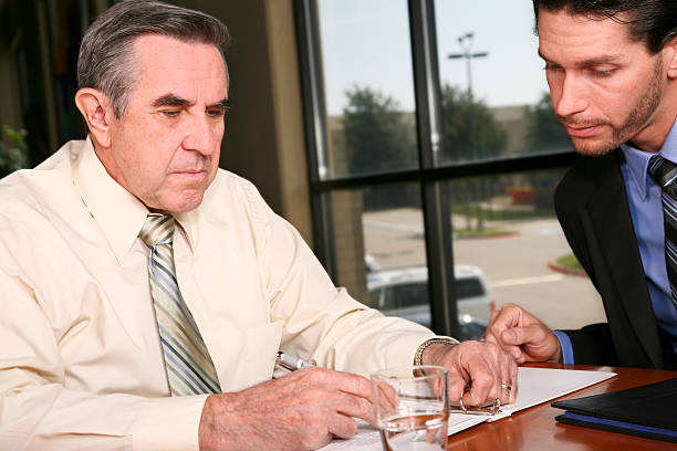 istock Well Dressed Man Filling Out Document with a Younger Person 176047471