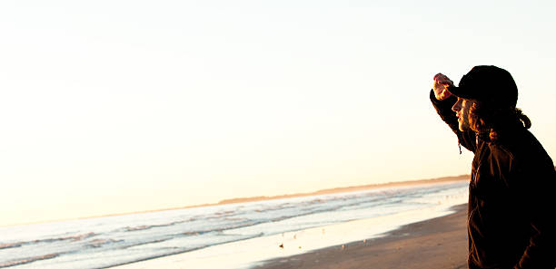 jeune homme regardant le lever du soleil au bord de l'eau - cumberland island flash photos et images de collection