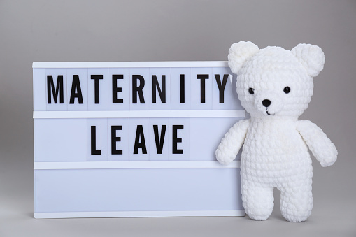 Lightbox with words Maternity Leave and toy bear on light grey background