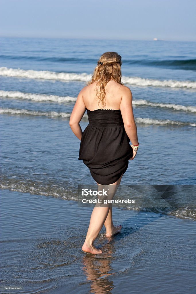 Giovane donna bionda con il vestito nero da pesca in mare - Foto stock royalty-free di Adolescente