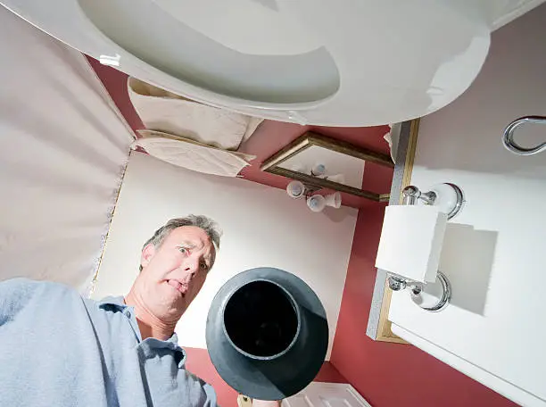 A man uses a plunger on a plugged toilet.