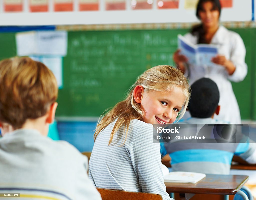 Portrait of a schoolgirl looking behind and smiling Portrait of a schoolgirl looking behind and smiling in classroom 10-11 Years Stock Photo