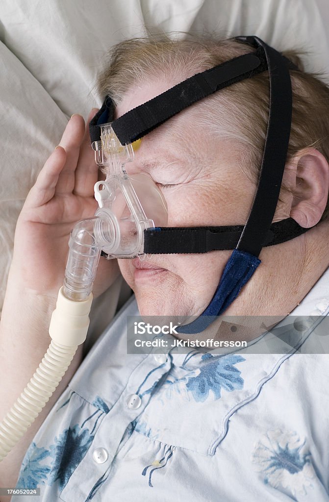 Senior Woman Sleeping with CPAP Mask Senior woman sleeping with CPAP (Continuous Positive Airway Pressure) mask to avoid breathing-holds/ apnea wich can be dangerous. One Woman Only Stock Photo