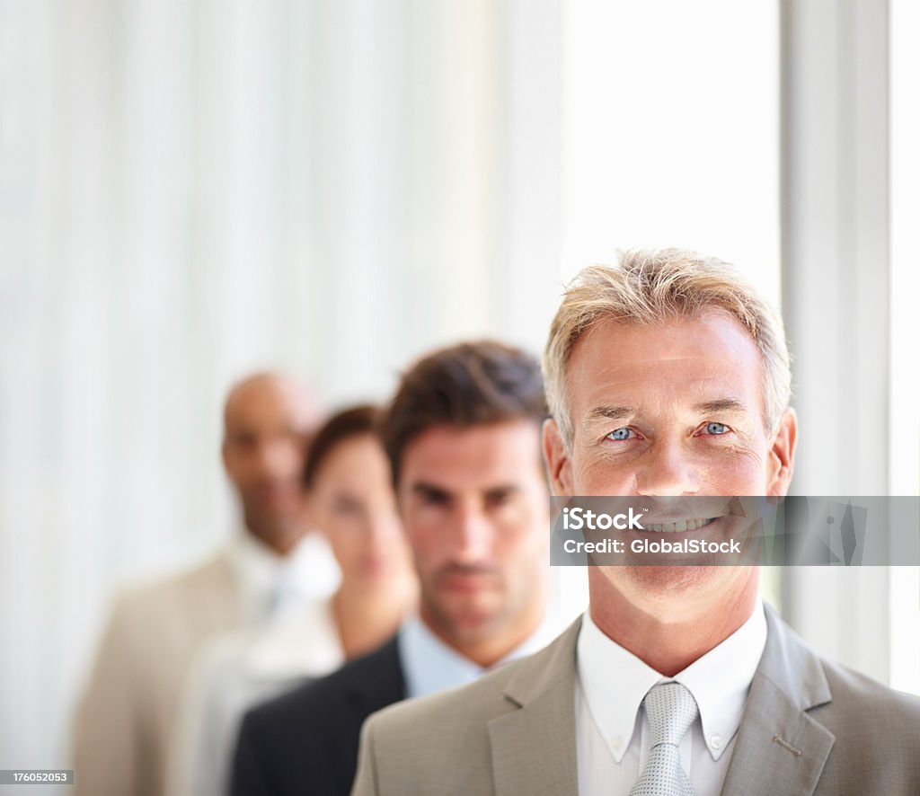 Sorridente maturo Uomo d'affari con i colleghi in background - Foto stock royalty-free di 20-24 anni