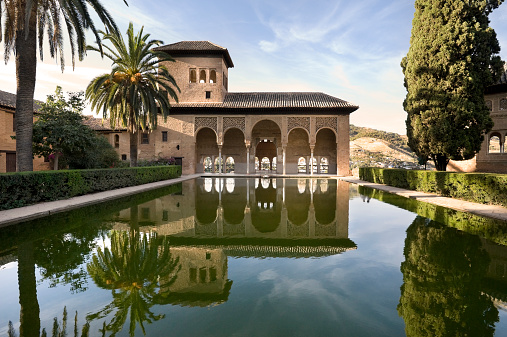 A view of an ancient palace at sunset at the Alhambra in Spain. A perfect mirrored reflection.