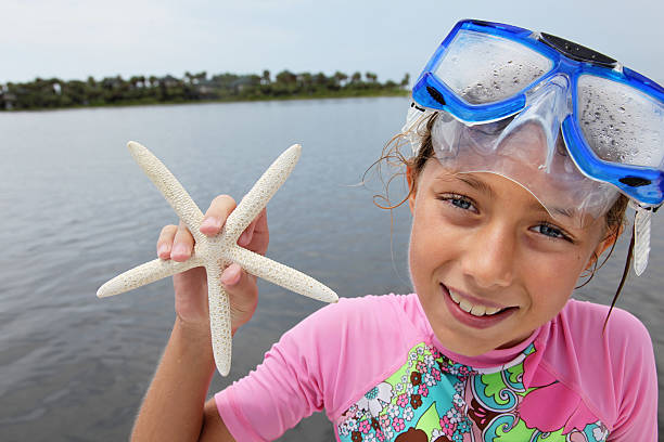 A beautiful little girl on Vacation in Florida fresh out of the water from snorkeling and holding the Starfish she found.