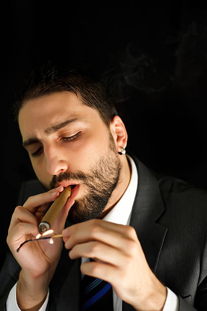 businessman smoking a cigar young businessman smoking a cigar lighting a cigar stock pictures, royalty-free photos & images