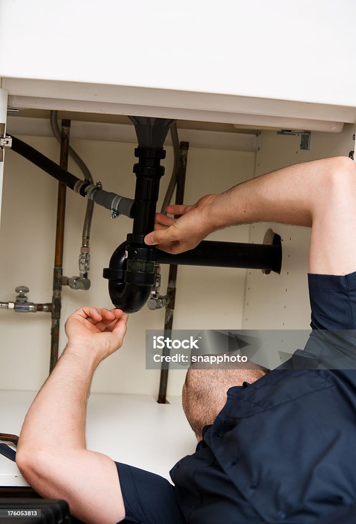 Uomo idraulico lavorando in cucina felice e uniforme e strumenti - Foto stock royalty-free di Adulto