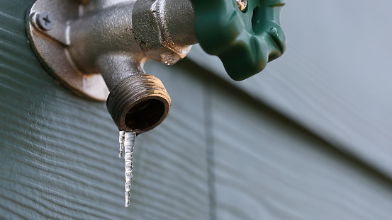 Photo of a frozen exterior faucet (hose bib) with icicles hanging from the end.