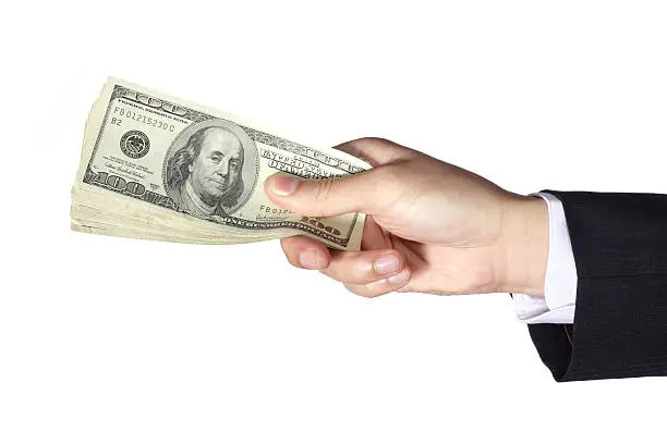 "A hand of a businessman holding stack of hundred dollar bills, isolated on white background."
