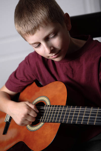 istock ten year old boy playing acoustic guitar 176056499