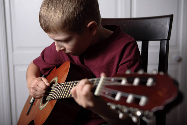 istock ten year old boy playing acoustic guitar 176056600