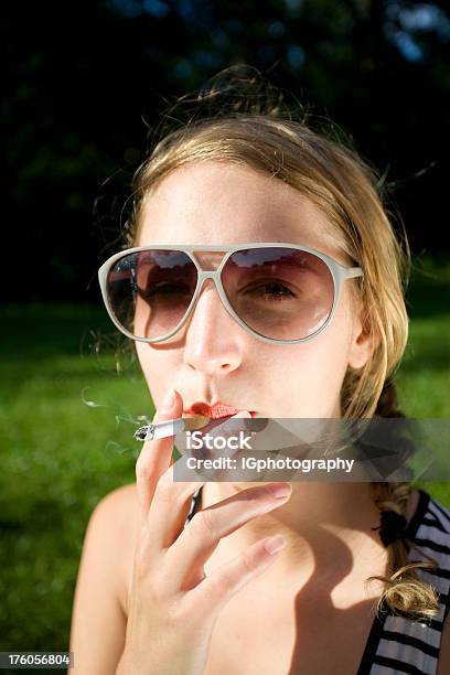Foto de Atraente Jovem Mulher Fumar Um Cigarro Com Óculos De Sol e mais fotos de stock de 1950-1959
