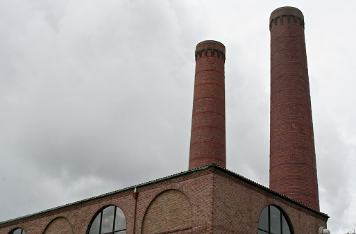 Smokestacks behind an old brick factory with a gloomy cloudy sky in the rear.  Plenty of copy space.