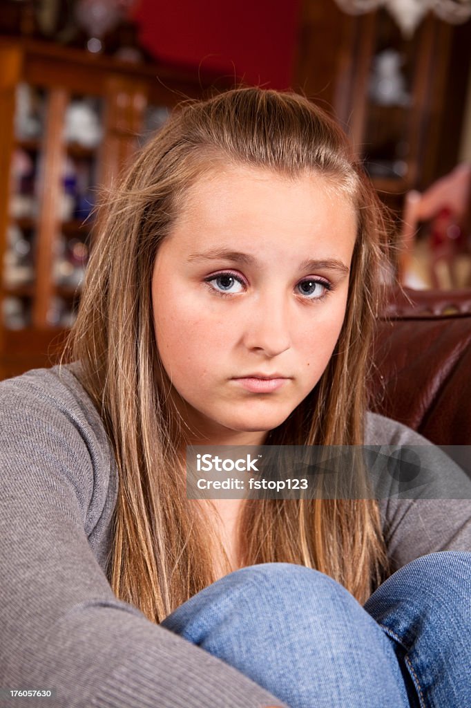 Moody teenage girl on sofa Moody teenage girl sitting on sofa and looking at camera. 14-15 Years Stock Photo