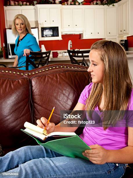 Adolescente Facendo I Compiti Sul Divano Mamma Lavora In Cucina - Fotografie stock e altre immagini di 14-15 anni