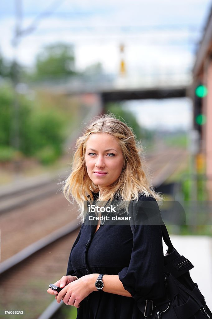 Jeune adulte avec téléphone mobile attend pour train - Photo de Adolescent libre de droits