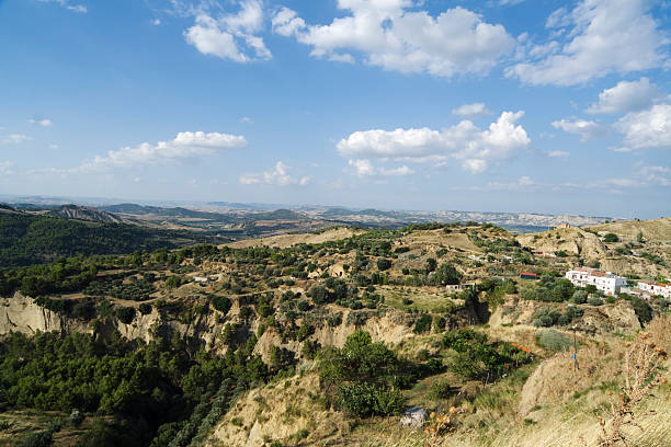 Rolling hills and fields under a partly cloudy sky in Sicily.