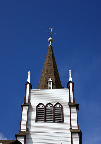 wooden tower of old church with cross on blue clear sky