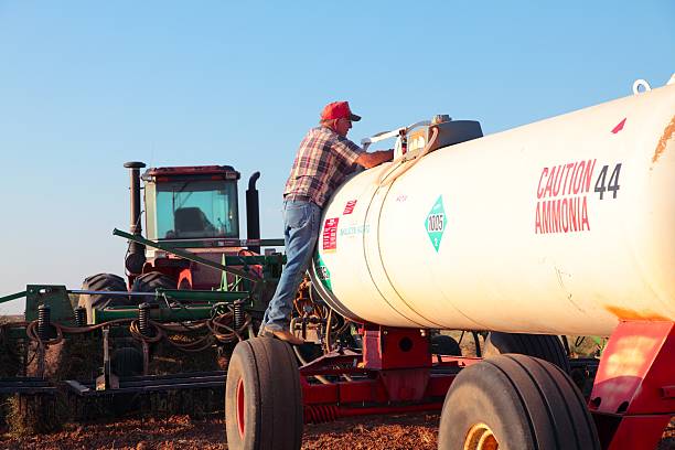 Agriculture: Farmer with Fertilizer Tank and tractor Farmer checking an anhydrous ammonia fertilizer tank. You can see tractor and plow in picture. Horizontal image would be good for agriculture use. ammonia fertilizer stock pictures, royalty-free photos & images