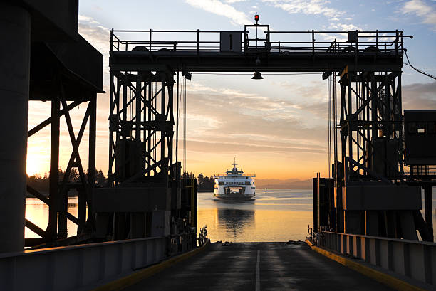 Ferry commuting to dock in the early morning Washington State car and passenger ferry arriving at Bainbridge Island ferry dock in the early morning sunrise. bainbridge island photos stock pictures, royalty-free photos & images