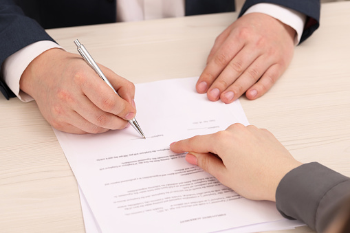 Close up of unrecognizable man signing a lease agreement on a meeting with his agent.