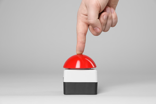 Man pressing red button of nuclear weapon on light gray background, closeup. War concept