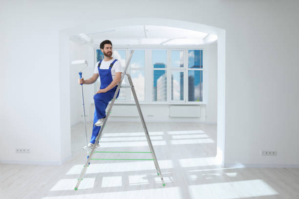 istock Handyman with roller on step ladder in room. Ceiling painting 1760623859