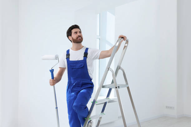 istock Handyman with roller on step ladder in room. Ceiling painting 1760623866