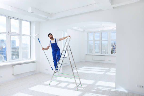 istock Handyman with roller on step ladder in room. Ceiling painting 1760623878