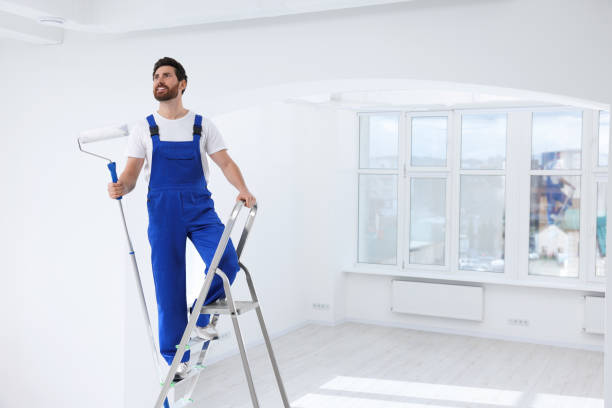 istock Handyman with roller on step ladder in room. Ceiling painting 1760624403
