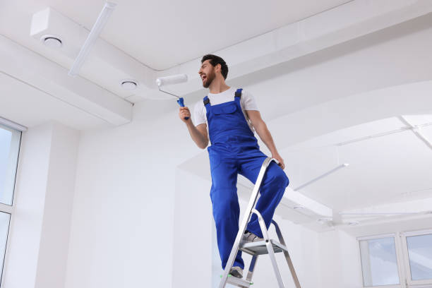 istock Handyman with roller having fun on step ladder in room, low angle view. Ceiling painting 1760624757