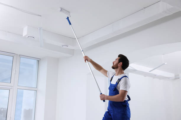istock Handyman with roller painting ceiling in room 1760625497