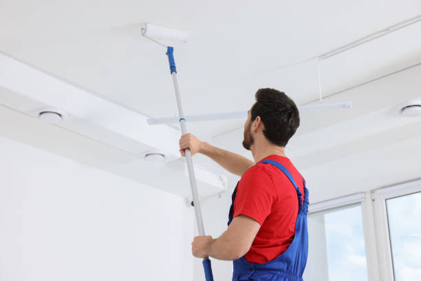 istock Handyman painting ceiling with roller in room, back view 1760625546