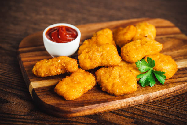 istock Semifinished chicken nuggets from chicken fillet on a dark background with fresh herbs. Quick cooking at home. Fast food. Breaded chicken nuggets. Breaded Chicken Inner Fillet. 1760627290