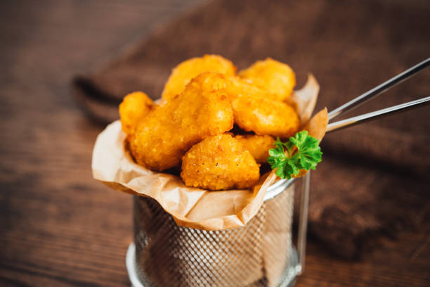istock Semifinished chicken nuggets from chicken fillet on a dark background with fresh herbs. Quick cooking at home. Fast food. Breaded chicken nuggets. Breaded Chicken Inner Fillet. 1760627292