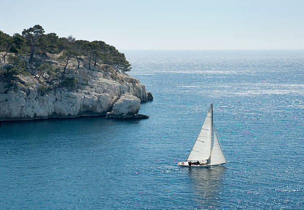 Sailing Past a Rocky Point on Mediterranean Coast stock photo