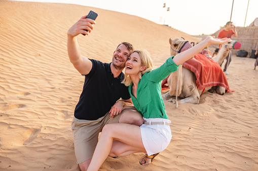 Tourists enjoying a truly authentic camel ride experience in the Dubai desert.
