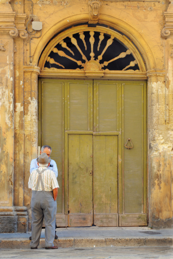 two men talking in front of an old entrance door in italy