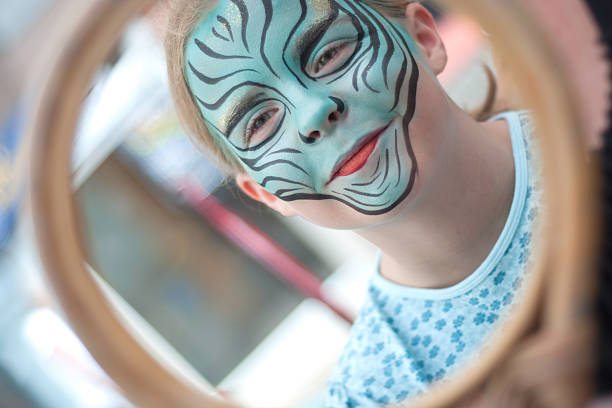 A girl looking in the mirror at her newly painted face.
