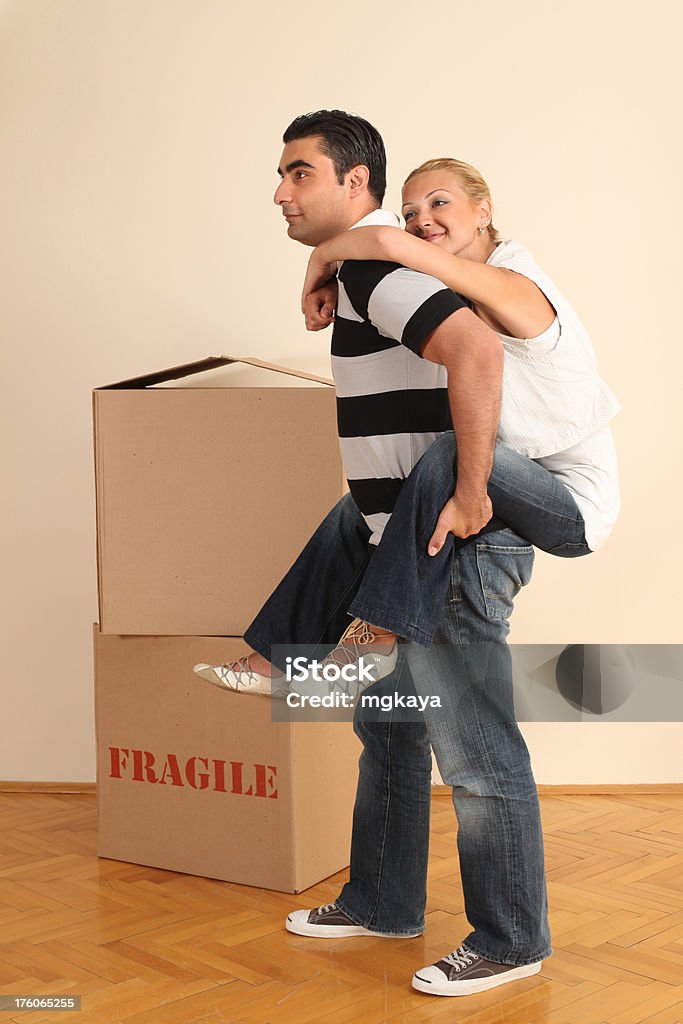 Young Couple Having Fun Young couple having fun at the moving day. Young man giving piggyback ride to young woman. 25-29 Years Stock Photo