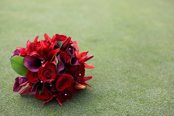 Brides Wedding bouquet in the cup on a putting green with red and purple flowers with copy space. shallow depth of field.
