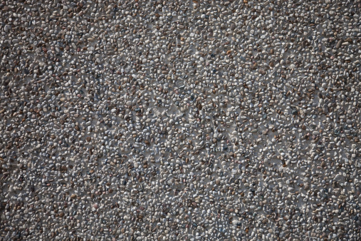 A picture of a cement wall with embedded pebbles.