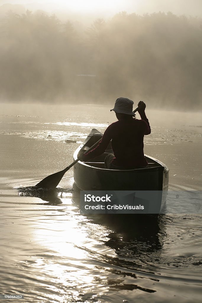 Garota ao ar livre, o remo canoa no lago no misty sunrise com iluminação de fundo - Foto de stock de Adolescente royalty-free