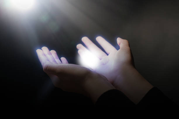 istock Woman stretching hands towards light in darkness, closeup. Praying concept 1760667314