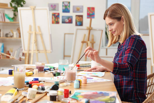 istock Beautiful woman painting at table in studio. Creative hobby 1760667887